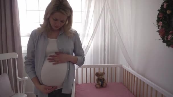 Gravid kvinna ledsen nära barnsäng hemma — Stockvideo