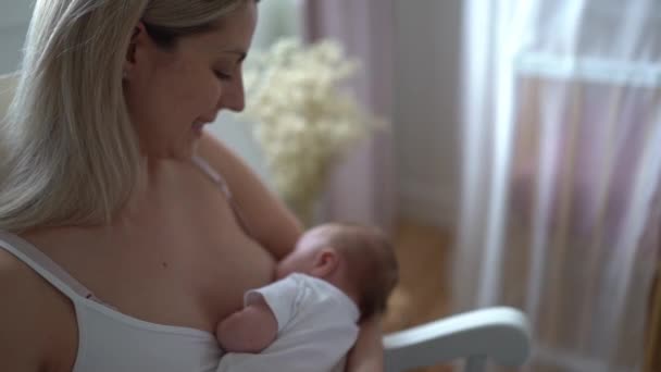 Een moeder die haar dochtertje borstvoeding geeft in haar armen. — Stockvideo