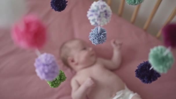 Zoetste baby meisje met een kleurrijke mobiele speelgoed — Stockvideo