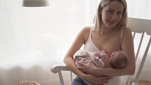 Een moeder die haar dochtertje borstvoeding geeft in haar armen. — Stockvideo