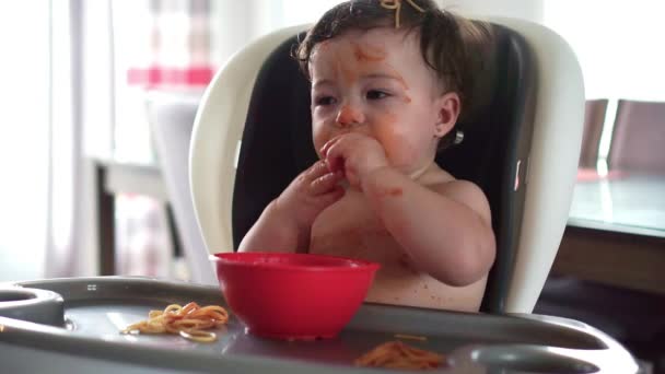 Child girl, eating spaghetti for lunch and making a mess at home in kitchen — Stock Video