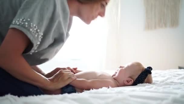 Moeder en baby meisje op een wit bed — Stockvideo