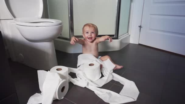 Niño rompiendo papel higiénico en el baño — Vídeos de Stock