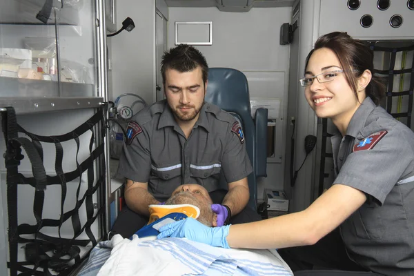 Ambulanciers professionnels donnant inconscient jeune femme premiers soins — Photo