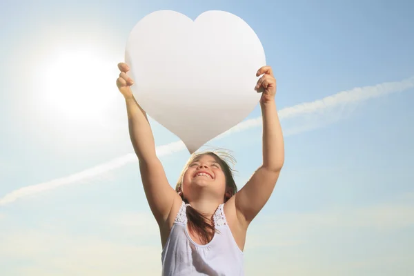 A young child holding heart over the sky — Stock Photo, Image