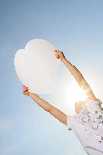 A young child holding heart over the sky — Stock Photo, Image