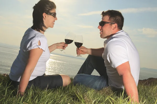 Um casal a beber uma garrafa de vinho tinto lá fora. — Fotografia de Stock