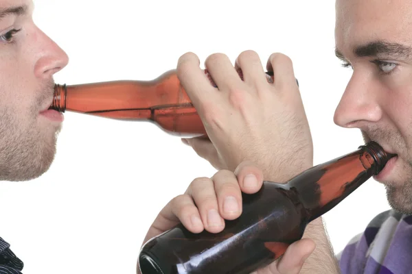 Casual young man holding bottle of beer, smiling. Isolated on wh — Stock Photo, Image