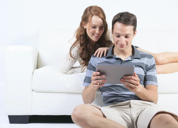 Een mooi paar op sofa met digitale tablet — Stockfoto