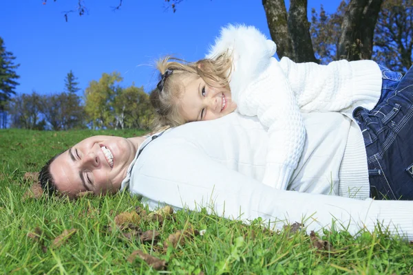 En familj njuter av golden lämnar i höst park — Stockfoto