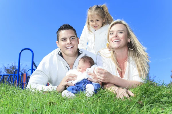 Eine fröhliche Familie lag im Gras eines Spielplatzes — Stockfoto
