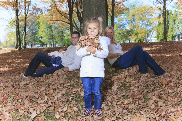 A Family enjoying golden leaves in autumn park — Stock Photo, Image