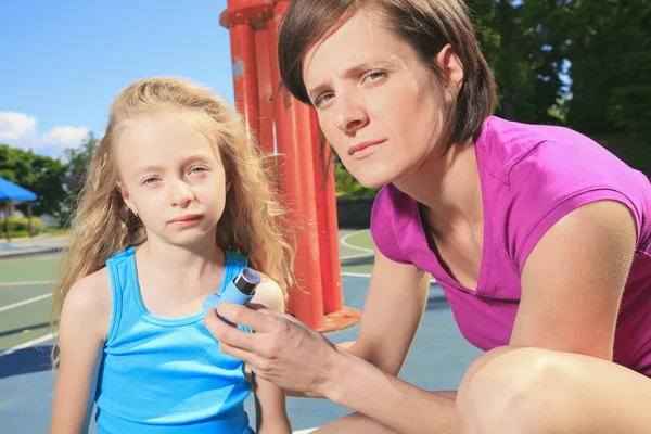 Мама использует ингалятор со своей дочерью-астматиком — стоковое фото