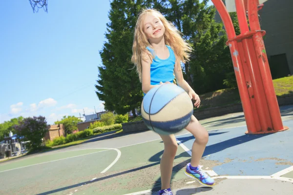 Una bambina gioca a basket con nel parco giochi — Foto Stock