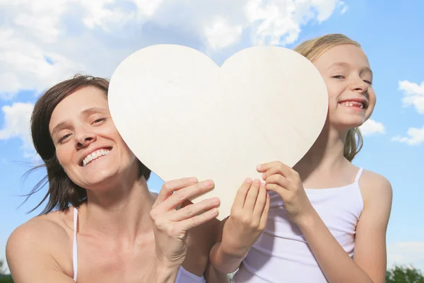 Liefhebbende moeder en daughterr, houden een hartvormige over de clo — Stockfoto