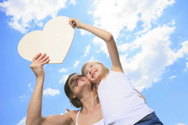 Loving mother and daughterr, holding a heart shaped over the clo — Stock Photo, Image