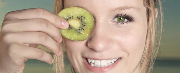 Porträtt av glad kvinna med kiwi halvor — Stockfoto