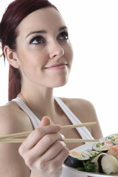 Jovem mulher comer um pedaço de sushi contra um fundo branco — Fotografia de Stock
