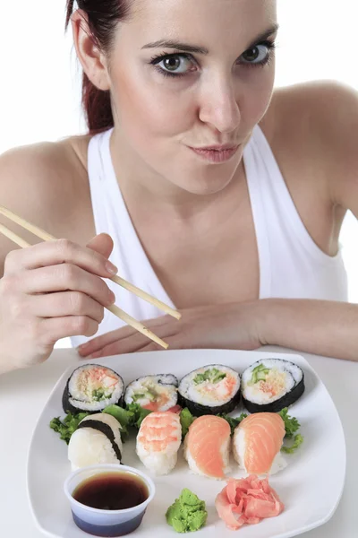Jeune femme mangeant un morceau de sushi sur un fond blanc — Photo