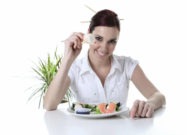 Jonge vrouw eten van een stukje sushi tegen een witte achtergrond — Stockfoto