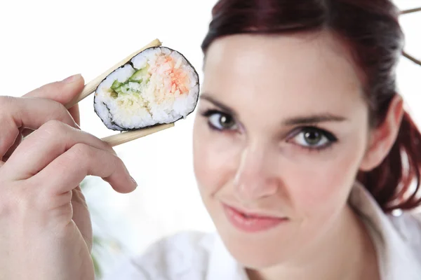 Mujer joven comiendo una pieza de sushi sobre un fondo blanco —  Fotos de Stock