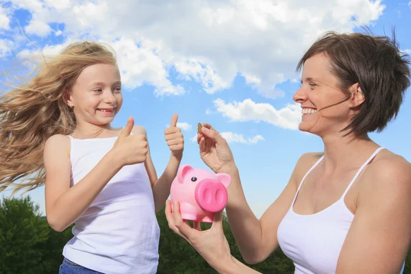 Um Piggy Bank and Coin segurando por uma menina Fotografia De Stock