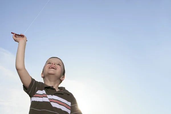 Chłopiec, który bawić jest latawiec z nieba na tle — Zdjęcie stockowe