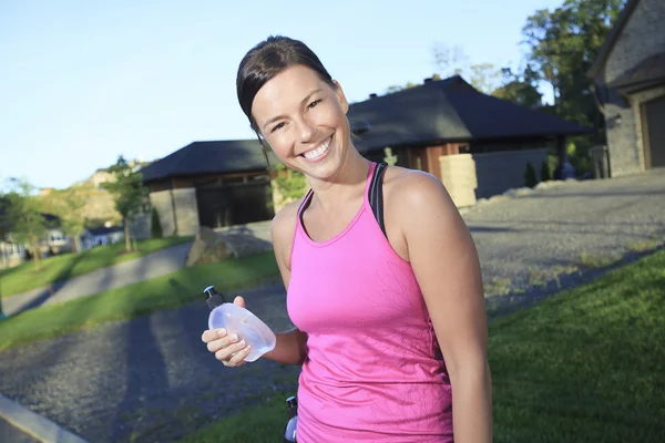 Une femme faisant du jogging dans un lieu urbain avec une maison en arrière-plan — Photo