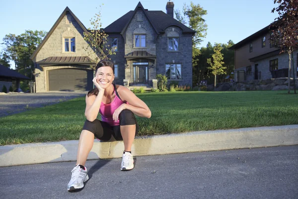 Une femme faisant du jogging dans un lieu urbain avec une maison en arrière-plan — Photo