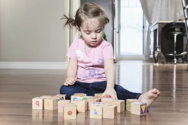 Красивая маленькая девочка, играющая с блоками на полу — стоковое фото