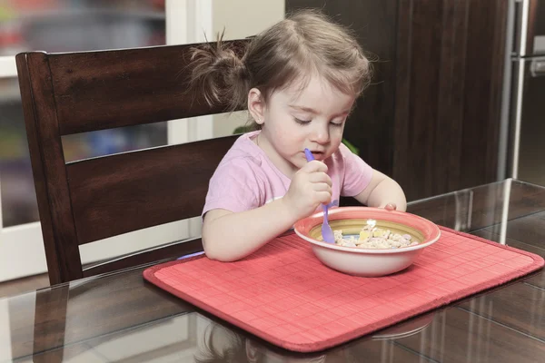 Schattige lachende meisje eten granen met de melk in de keuken — Stockfoto