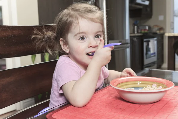 Schattige lachende meisje eten granen met de melk in de keuken — Stockfoto
