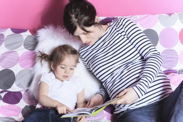 Madre e hija joven leyendo libro en el dormitorio — Foto de Stock