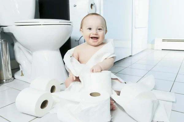 Criança rasgando papel higiênico no banheiro — Fotografia de Stock