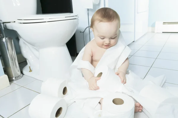 Peuter scheurt wc-papier in de badkamer — Stockfoto