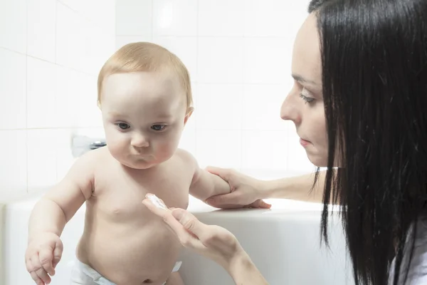 Madre dando crema a su hijo bebé después del baño — Foto de Stock