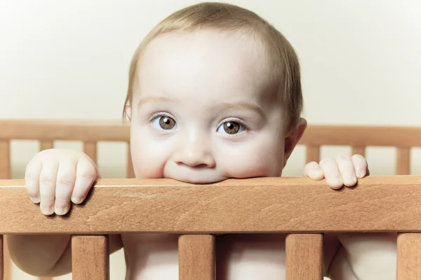 Funny little baby with beautiful standing in a round white crib — Stock Photo, Image
