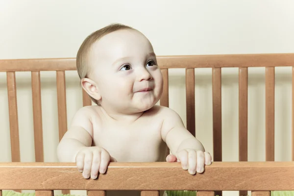 Petit bébé drôle avec une belle debout dans une crèche ronde blanche — Photo