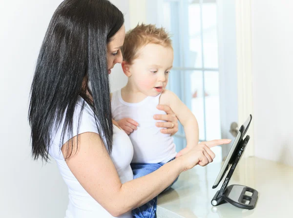 Mãe e bebê menino usando tablet digital na cozinha em casa — Fotografia de Stock