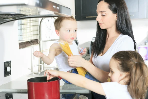 Une famille cuisine des pâtes à l'intérieur de la cuisine — Photo