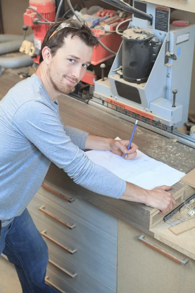 An adult carpenter measuring wood with ruler at table in worksho — Stock Photo, Image