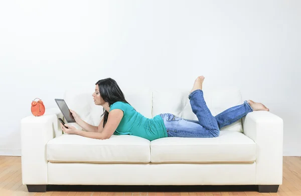 Jonge vrouw met behulp van elektronische tablet zittend op de Bank — Stockfoto