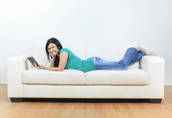 Jonge vrouw met behulp van elektronische tablet zittend op de Bank — Stockfoto