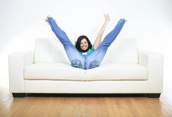 Una bella donna sorridente che si rilassa sul divano — Foto Stock