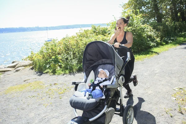 En ung mamma joggar med en barnvagn — Stockfoto