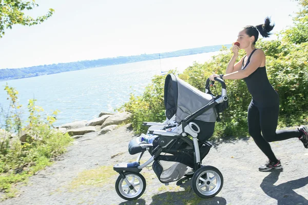 Una giovane madre che fa jogging con una carrozzina — Foto Stock