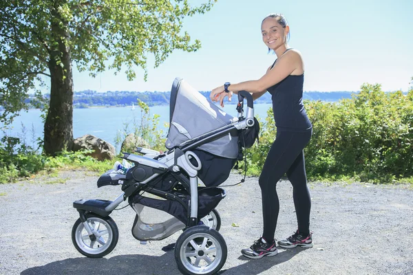 En ung mamma joggar med en barnvagn — Stockfoto