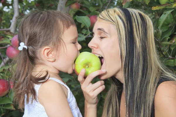 Een moeder spelen met haar dochter op appelboom — Stockfoto