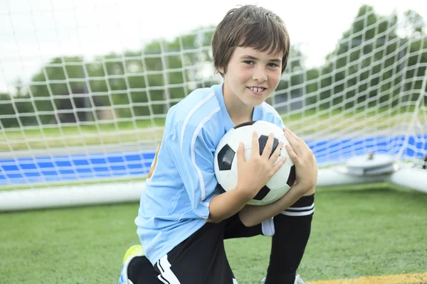 Mladý fotbalista s míčem na hřišti — Stock fotografie