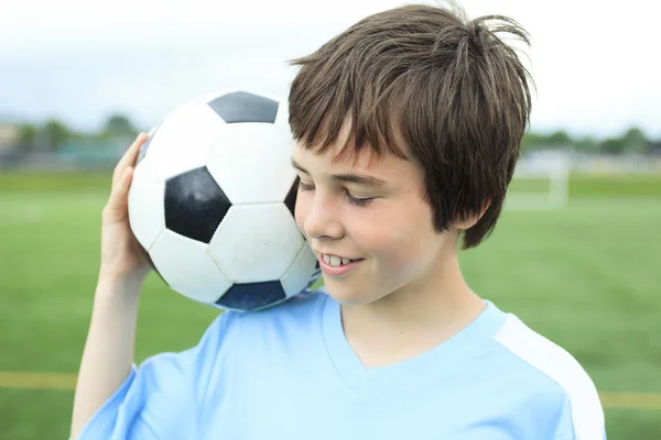 En ung fotbollsspelare med bollen på fältet — Stockfoto